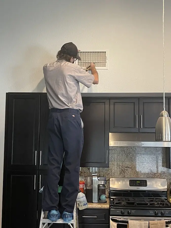 Technician inspecting an air vent during HVAC service in Brier